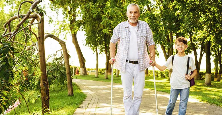 Man walking in the woods with crutches which helps a torn knee ligament to recover following injury