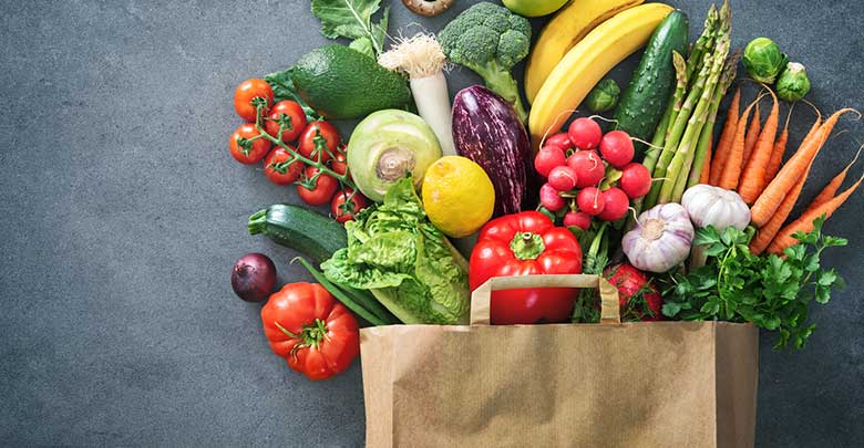 A brown paper grocery bag overflowing with healthy fruits and vegetables 