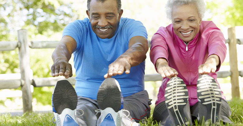 An older couple do their exercise for arthritis outside in the dappled sunshine. 