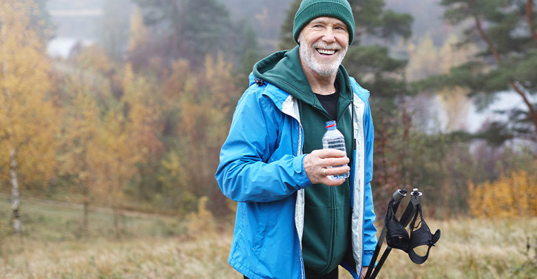 The best exercise to lose weight is walking - here an older man is hiking in the forest to get the benefits of exercising for weight loss and osteoarthritis.